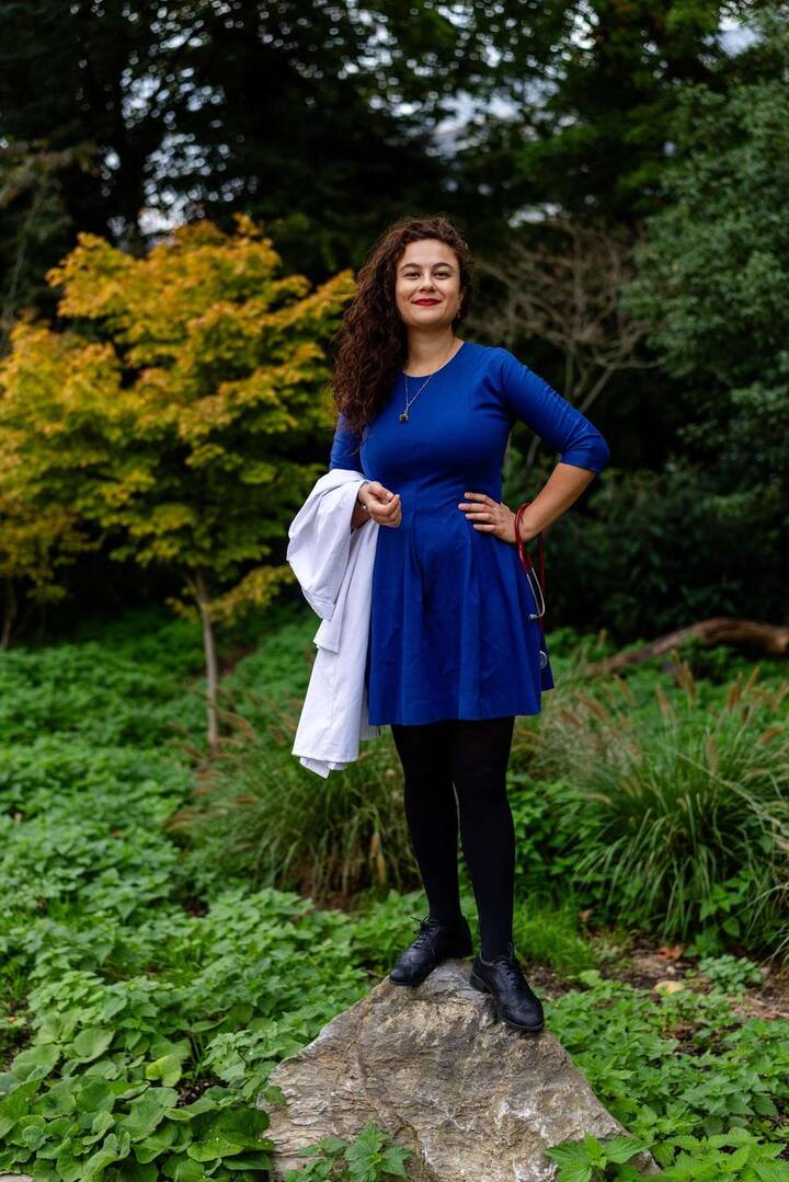 Sarai Keestra in a garden, holding a white coat and a stethoscope